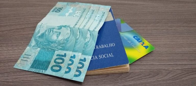 imagem com dinheiro, carteira de trabalho e carteirinha da CAIXA